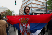 A man holds a Serbian flag, as students block access to the state broadcaster Radio Television of Serbia (RTS), demanding fair and unbiased reporting, in Belgrade