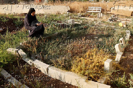 Palestinians visit graves of their relatives at a cemetery in Jenin camp