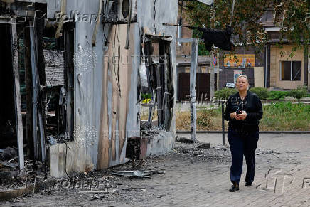 A shop owner shows the damage to her store following the shelling of a market in Donetsk
