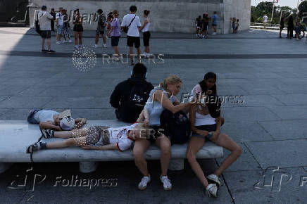 Tourists seek relief in the shade created by the Washington Monument during a heatwave affecting the eastern U.S., in Washington