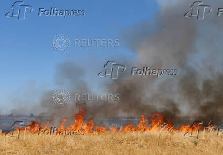 Flames burn across hillside at brushfire in Woodland California