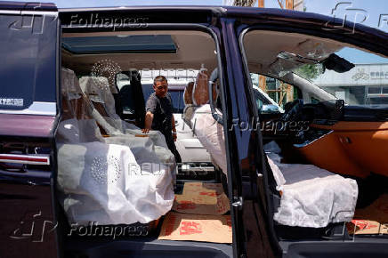 Salesperson checks the interior of a second hand Hongqi HQ9 PHEV at a used car market in Beijing