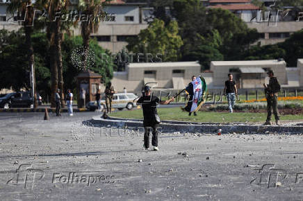 People gather near a damaged site, in Damascus