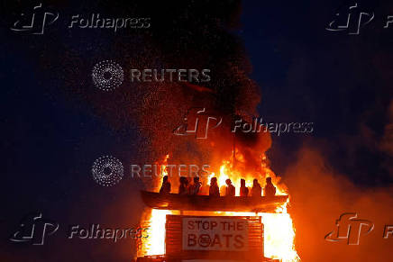 Bonfire burns with effigy of migrants in a boat atop it, in Moygashel