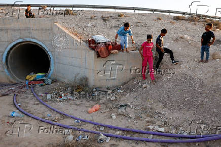 Bedouin children stand outside a tunnel under a bridge they use as a shelter in case of a rocket siren alert for a missile strike from Iran on Israel, in southern Negev