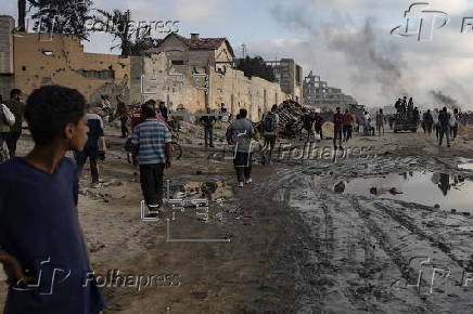 Displaced Palestinians carry relief parcels along Rashid Street, west of Gaza City