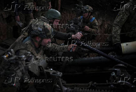 Servicemen fire a howitzer towards Russian troops at a position on front line in Donetsk region