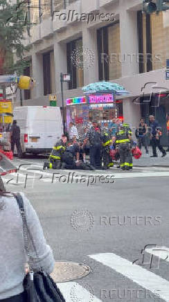Police officers try to rescue an injured man next to a Midtown Manhattan skyscraper, in New York