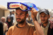 Palestinians carry aid supplies they received from the U.S.-backed Gaza Humanitarian Foundation, in Khan Younis