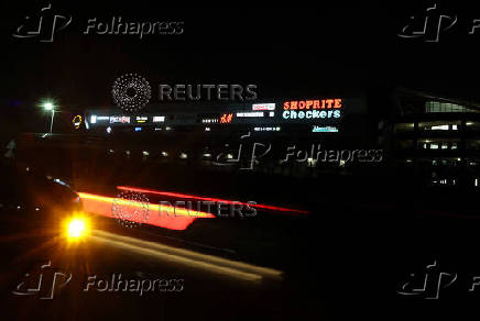 Cars drive past a shopping mall displaying logos of shops in southern Johannesburg