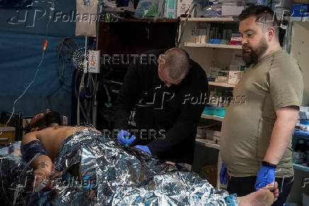Medics help a wounded Ukrainian serviceman at a medical stabilisation point, near the town of Pokrovsk, in Donetsk region