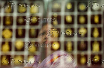 FILE PHOTO: A customer checks gold ornaments at a jewellery shop in the old quarters of Delhi