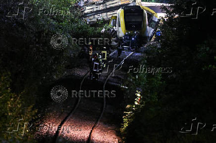 Emergency personnel work at the site where a passenger train derailed in southwestern Germany