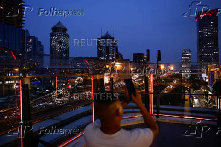 A person takes pictures on a terrace of a shopping mall overlooking the central business district (CBD), in Beijing