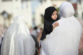 A girl is carried by her mother as Indonesian Muslims attend mass prayers during Eid al-Adha celebrations at Baiturrahman Mosque in Banda Aceh