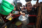 Palestinians wait to receive food from a charity kitchen, in Gaza City