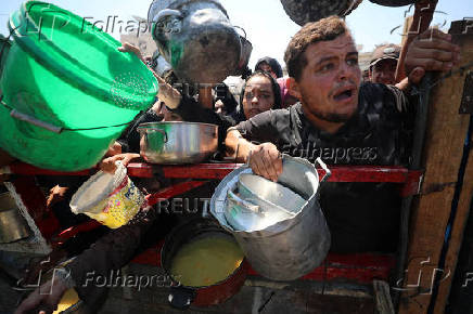 Palestinians wait to receive food from a charity kitchen, in Gaza City
