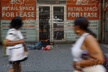 A woman sleeps on the sidewalk outside empty real estate along 34th street in Manhattan, New York City