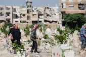 People visit the graves of their relatives at a cemetery, on the first day of the Muslim holiday of Eid al-Adha, in Damascus
