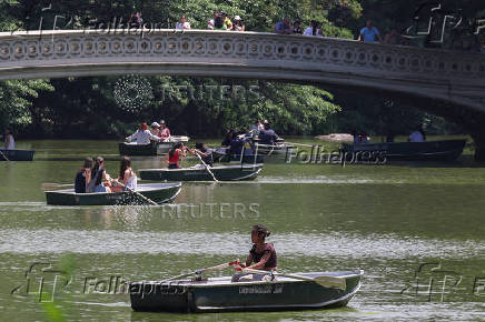 People ride rowboats in the Central Park lake during an extreme heat warning in New York