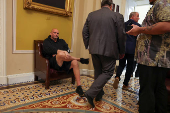 U.S. Senator Fetterman sits in the hallway behind the weekly Senate Democrat press conference at Capitol in Washington