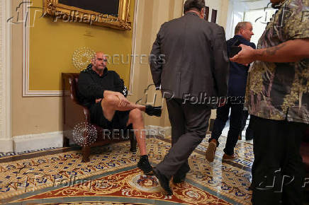 U.S. Senator Fetterman sits in the hallway behind the weekly Senate Democrat press conference at Capitol in Washington