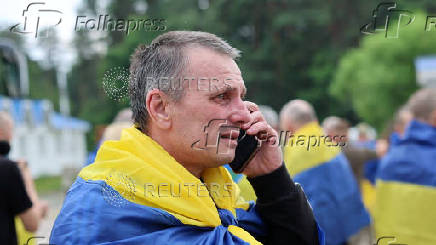 Ukrainian POWs speaks with relatives via a phone after a swap at an unknown location in Ukraine