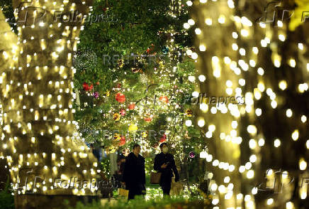 People walk under lights celebrating the upcoming the Christmas season at a park in Tokyo
