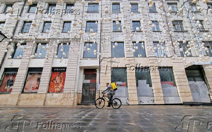 FILE PHOTO: A courier rides a bicycle past the temporarily closed Prada shop in Moscow