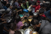 Displaced Palestinians collect donated food in Jabalia, northern Gaza