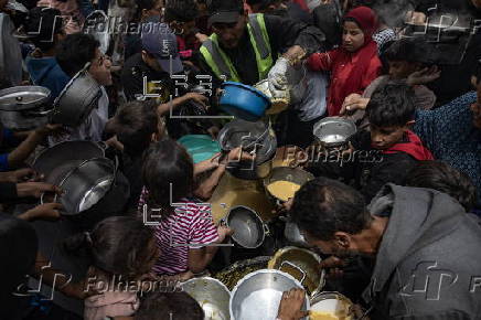 Displaced Palestinians collect donated food in Jabalia, northern Gaza