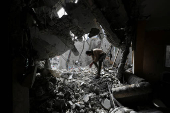 Palestinians inspect the site of an Israeli strike on a house, in Gaza City