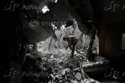 Palestinians inspect the site of an Israeli strike on a house, in Gaza City