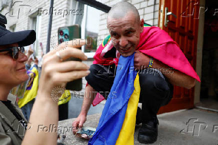 Ukrainian prisoner of war reacts as he speaks with his relatives via a phone after a swap in an undisclosed location in Ukraine