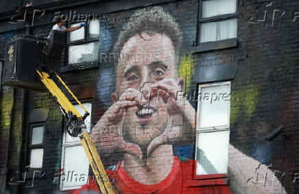 Artist John Culshaw works on a mural of late Liverpool player Diogo Jota on the side of a pub in Liverpool