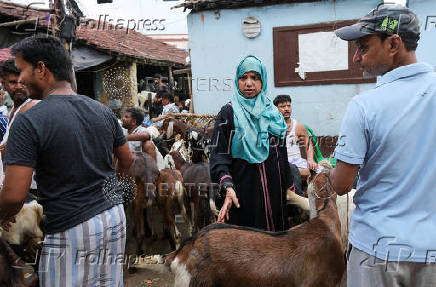 A woman inspects goats before purchase, inside a livestock market ahead of the Eid al-Adha festival in Kolkata
