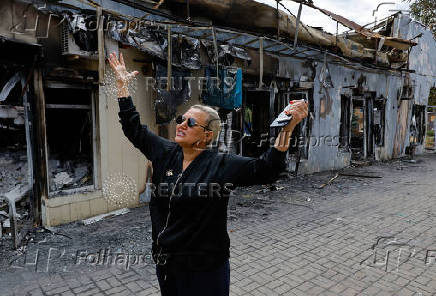 A shop owner shows the damage to her store following the shelling of a market in Donetsk