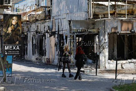 People stand next to the shops damaged by recent shelling of the market in Donetsk