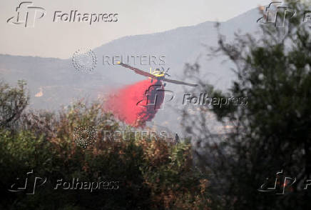 A firefighting airplane drops fire retardant to extinguish fire in Omodos village