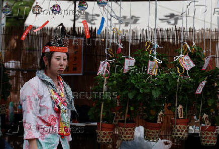 A vendor, selling Japanese lantern plants, wears a towel on her head to cope with the heat wave at the Hozuki-Ichi (Japanese lantern plant fair) at Sensoji temple, in Tokyo