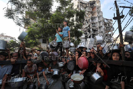 Palestinians wait to receive food from a charity kitchen, amid a hunger crisis, in Gaza City