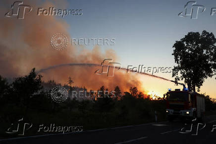 Firefighters work to extinguish a wildfire in Gohrischheide