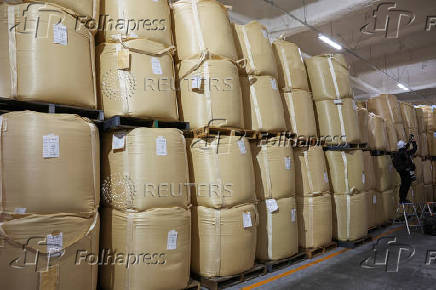 A photographer takes a photo of sacks of stockpiled rice at a warehouse in Kanagawa