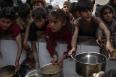 Displaced Palestinians collect donated food in Jabalia, northern Gaza