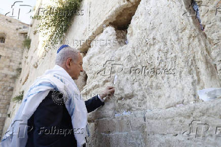 Israeli Prime Minister Benjamin Netanyahu places a note in between the bricks of the Western Wall