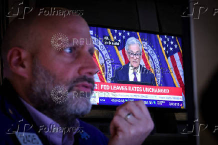 A trader works, as a screen broadcasts a news conference by U.S. Federal Reserve Chair Jerome Powell following the Fed rate announcement, on the floor of the NYSE in New York