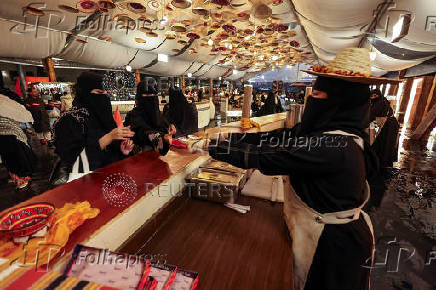 A Saudi woman sells local food to visitors at a Cultural and Heritage Festival in downtown Abha, Saudi Arabia