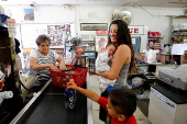 FILE PHOTO: Hernandez holds newborn at the Save Money Market checkout in the historic mining town of Superior, Arizona