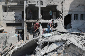 Palestinians inspect the damage at the site of an Israeli strike on a house, in Gaza City