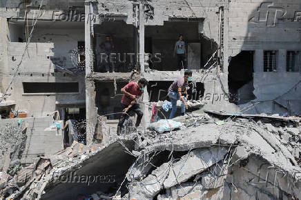 Palestinians inspect the damage at the site of an Israeli strike on a house, in Gaza City